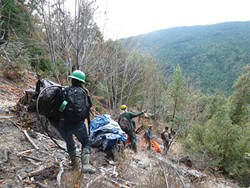 PHOTO BY RYAN BURNS - A crew of volunteers descends a hill near the Humboldt-Trinity County border while Army National Guard soldiers help coordinate.