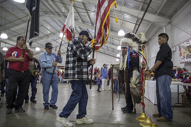 An elder veteran carries an American flag during the part of the ceremony honoring veterans. - MANUEL J. ORBEGOZO