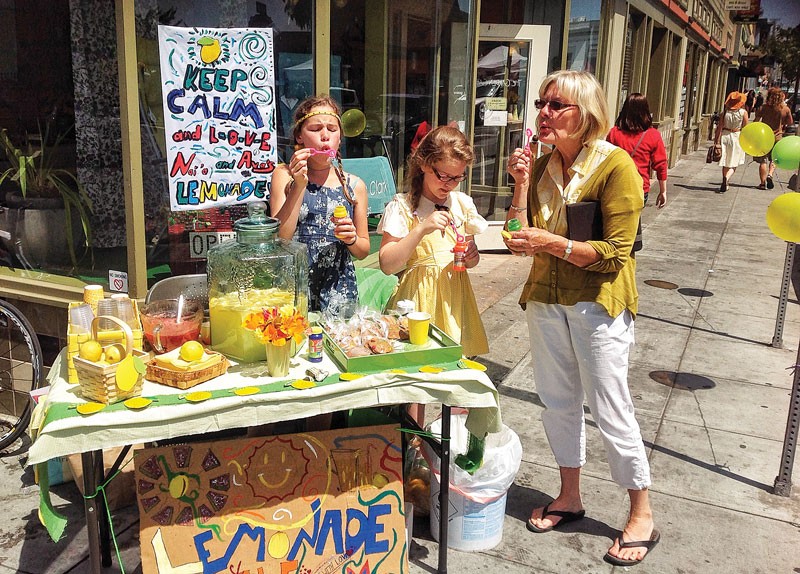 Ava Berg, Naia Ryman and Ava's grandmother, Siv Berg, blow bubbles to attract customers to their Lemonade Day booth in front of Arcata's Garden Gate on Saturday, June 7. - PHOTO BY BOB DORAN