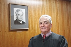 PHOTO BY THADEUS GREENSON - Humboldt County Superior Court Judge W. Bruce Watson stands in front of a portrait of his father, the late Judge William Watson Jr. Watson has announced that he will retire in January, after 23 years on the Humboldt County bench.