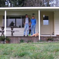 Scott and Linda Powell with their daughter and the family dog on the porch of their Dow's Prairie Mobile Home.