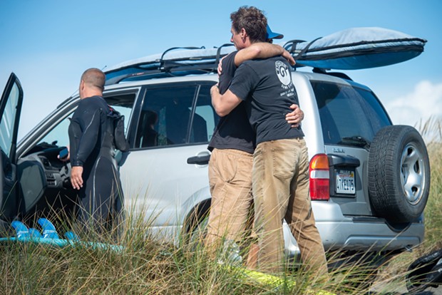 Jim Merryfield, one of four regular surfers at the North Jetty who rendered aid to Hargrave, hugs a friend on the dunes shortly after returning to shore. All four of the surfers described Hargrave as a great guy and experienced surfer. - MARK MCKENNA