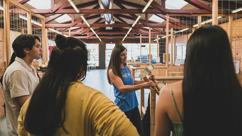Lauren Fischer shows newbies the basics of ax-throwing. - CONNOR RAY PHOTOGRAPHY