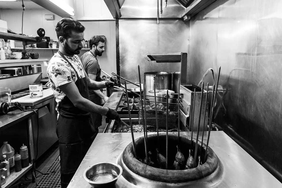 Gurpinder Singh manages the fryer and tandoor, while chef Dalbir Singh cooks a pot of curry. - AMY KUMLER