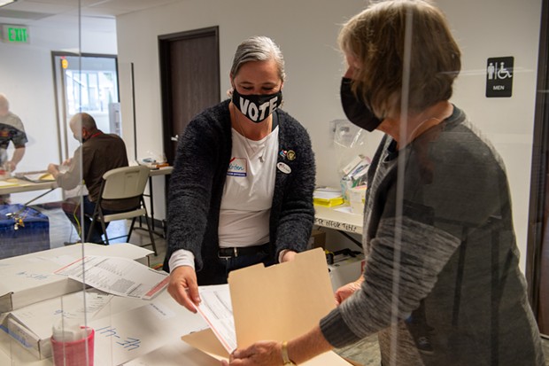 Poll worker Kristen Porter, left, places a ballot in a folder held by Julie Fulkerson at the Eureka Pentecostal Church on Hoover Street. Porter has worked several elections while Fulkerson was working her first at the polls. - MARK MCKENNA