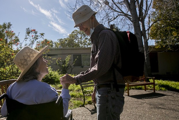 Larry Yabroff and his wife Mary greet each other during a visit at Chaparral House, a skilled nursing facility where Mary is a resident, in Berkeley on Feb. 25, 2021. Because both are vaccinated, the facility allows them to have non-socially distanced visits. Most California facilities, however, will not allow in-person visits. - PHOTO BY ANNE WERNIKOFF, CALMATTERS