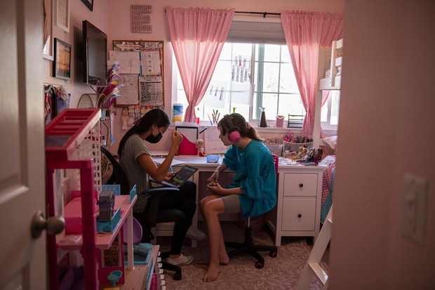 Ellie sits in her room with a behavioral therapist during class time in Monrovia, on Sept. 15, 2021. "There is no way to go back with 37 kids in a classroom," Julie Fitzgibbons, the mother of triplets, said. "With masks and not being able to communicate very well, and autism, there is just no way we can go back like normal." - PHOTO BY PABLO UNZUETA FOR CALMATTERS