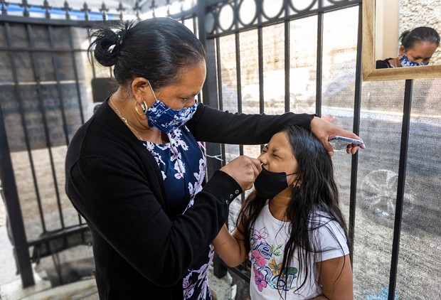 Maria Jimenez swabs her 7 year old daughter, Glendy Perez, for a COVID-19 test at Canal Alliance in San Rafael on Sept. 25, 2021. - PHOTO BY PENNI GLADSTONE FOR CALMATTERS