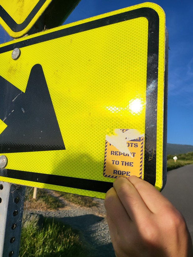 A reader removing a threatening anti-LGBTQ+ sticker from a sign at the Arcata Marsh. - SUBMITTED