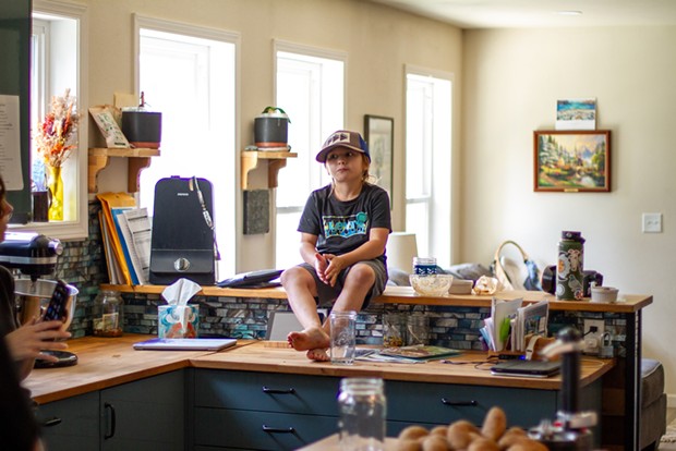 Morek O'Rourke, 7, sits on the counter eating homemade smoked salmon dip as he tells his parents a story.
