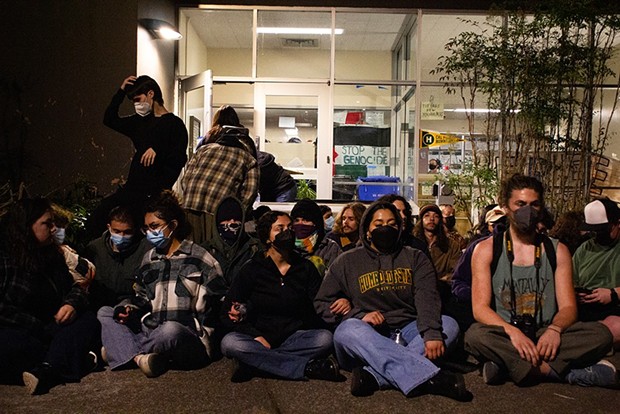 Protesters sit outside the barricaded entrance of Siemens Hall, interlocking arms, on April 22, in an effort to prevent officers from attempting to enter the building. - PHOTO BY ALEXANDER ANDERSON