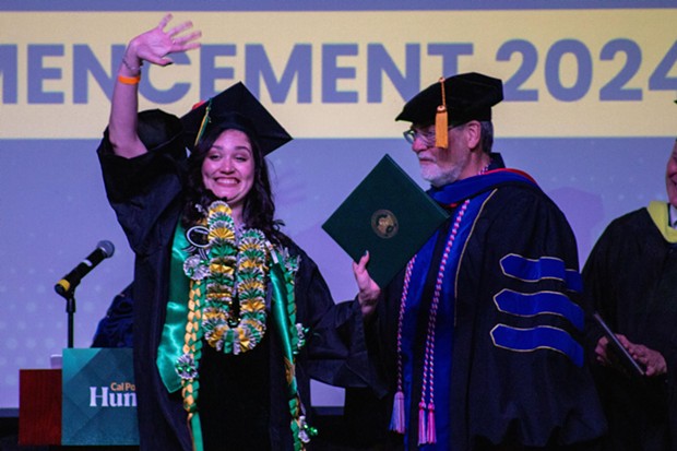 Cal Poly Humboldt graduate Violet Zoe Becerra waves to the crowd while receiving a Bachelor of Arts degree at Blue Lake Casino. - PHOTO BY GRIFFIN MANCUSO
