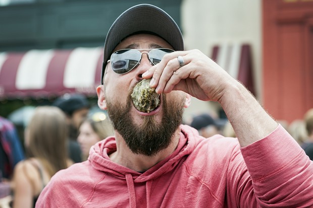 Adam Dietrich takes down an Oyster from the Humboldt Made booth at the 25th Annual Oyster Festival. - MARK MCKENNA