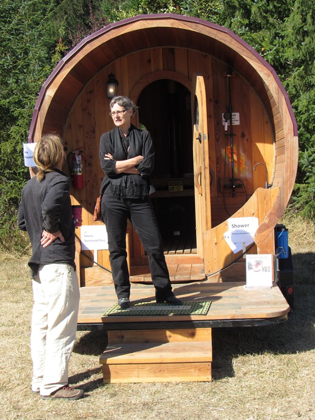 Janelle Egger stands on the porch of a tiny house with its own shower and toilet. - LINDA STANSBERRY