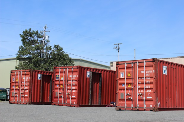 Shipping containers sit in the lot at the corner of Third and Commercial Streets, with renovations having already begun. - THADEUS GREENSON