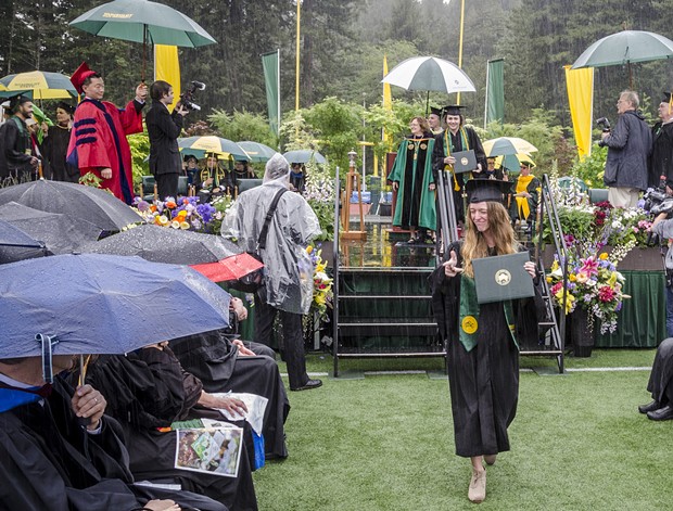 Journalism graduate Rebekah Staub displayed her diploma as she left the stage in a downpour at the College of Arts, Humanities and Social Sciences commencement on Saturday morning, May 14 in HSU's Redwood Bowl. - MARK LARSON