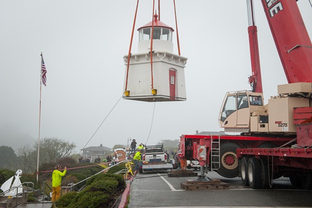 Two workers use ropes to align the lighthouse as it is moved to a trailer. - MARK MCKENNA