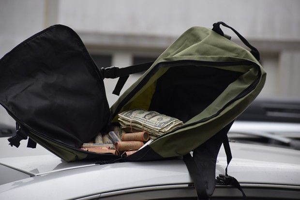 A backpack full of cash and coins pulled from the suspect vehicle. - THADEUS GREENSON
