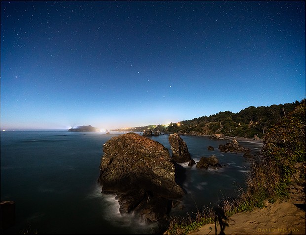 At the western edge of the North American continent, on the rough shores of the great Pacific Ocean, Trinidad, Humboldt County, California, sparkles in the moonlight under a starry sky. The Big Dipper and Polaris, the North Star, have been enhanced for recognizability.