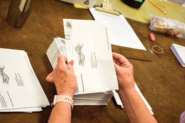 A volunteer prepares vote-by-mail ballots for counting in 2018.
