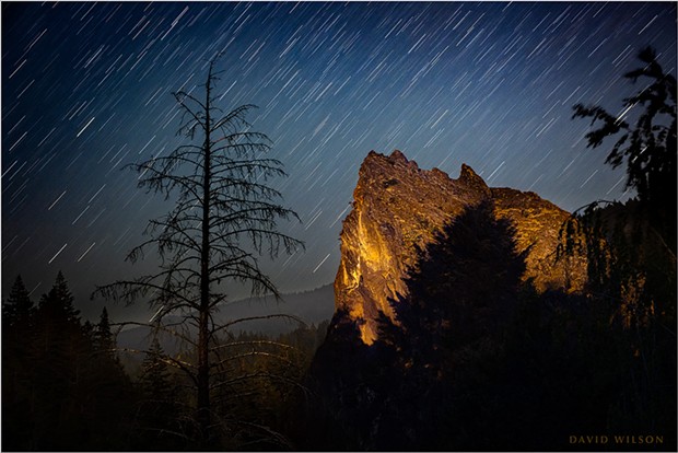 A great rock outcrop rests in a remote river valley beneath the stars on California's North Coast. Moonlight illuminated the landscape beyond, while some light from nearby human activity temporarily shone upon the rock itself in this 346-second exposure. July 13, 2021.