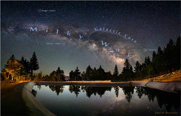 Ringed by trees, a giant catchment pond reflects the magnificent sky at Schackow Farm in Humboldt County. A crescent moon sinking in the west illuminates the far hills across the Eel River Valley. The galactic core will sink beneath the horizon a little each night through the fall until it is no longer visible in our night sky, to return after the spring. June, 2021.