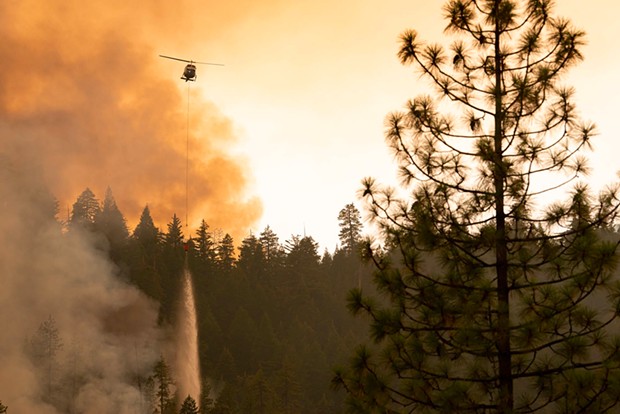 A helicopter drops water on the edge of the McFarland Fire.