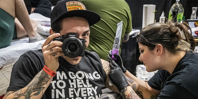 Yinnre Dedon, of Chicago, mugged with his camera while getting a tattoo by artist Shayna Behrens of Golden Gator Tattoo shop in Fortuna.