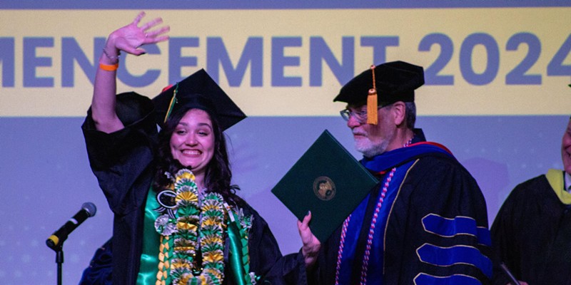 Cal Poly Humboldt graduate Violet Zoe Becerra waves to the crowd while receiving a Bachelor of Arts degree at Blue Lake Casino.