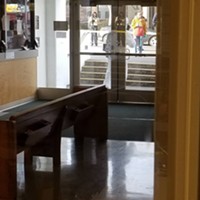 A Hazmat suit protects personnel outside of the Courthouse Clerk’s Lobby as seen from inside the lobby.