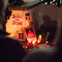 A Justice for Josiah sign and posters of Lawson illuminated by candlelight at the vigil.