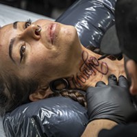 Tattoo artist David Chavera, of Local Boy Tattoo in San Antonio, Texas, preps a "Much Love" design in Spanish on the neck of Roxanne Reche, of Willow Creek.