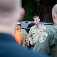 Sheriff William Honsal looks on during a debriefing with search teams returning from the field.