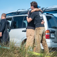Jim Merryfield, one of four regular surfers at the North Jetty who rendered aid to Hargrave, hugs a friend on the dunes shortly after returning to shore. All four of the surfers described Hargrave as a great guy and experienced surfer.