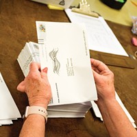 A volunteer prepares vote-by-mail ballots for counting in 2018.