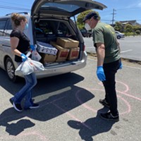 Volunteers load food into the trunk of a waiting car at a recent food distribution.