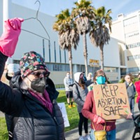 Erin Sullivan, wearing a pink glove and waving a coat hanger was one of dozens who turned out to support reproductive health at the courthouse on Tuesday.