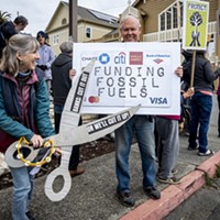 Annette Holland, of Arcata, symbollically cuts up a bank card held by Greg Holland at the Third Act protest in front of Wells Fargo Bank in Arcata.