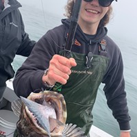 Eric Howard, a deckhand for Brookings Fishing Charters, holds a lingcod caught last week aboard the Miss Brooke while fishing out of Brookings, Oregon. The lingcod latched onto a blue rockfish.