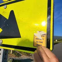 A reader removing a threatening anti-LGBTQ+ sticker from a sign at the Arcata Marsh.