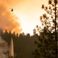 A helicopter drops water on the edge of the McFarland Fire.