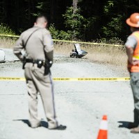 What appears to be part of a plane engine and propeller lie on an access road near the crash site.