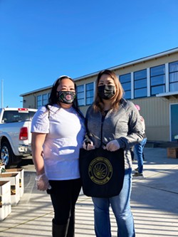 PHOTO BY JENNIFER FUMIKO CAHILL - Mai Cheng and Yanli Yang of New Rising Hmong Association with a bag full of Hmong language health information, masks and sanitizer to be handed out with the food.