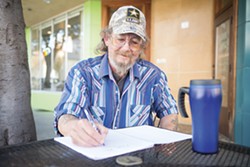 PHOTO BY MARK MCKENNA - Bob Hager writes in his notebook in front of Because Coffee in Eureka.